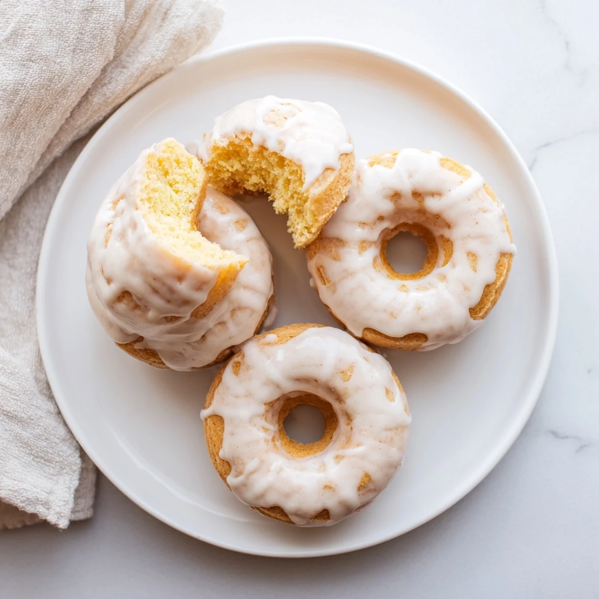 Golden baked Greek yogurt cake donuts glazed with vanilla icing on a wire rack