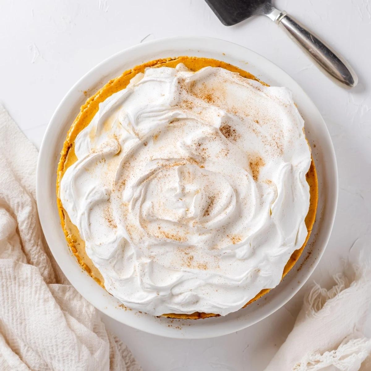 Sliced pumpkin spice Christmas cheesecake showing smooth orange filling with dollops of fresh whipped cream