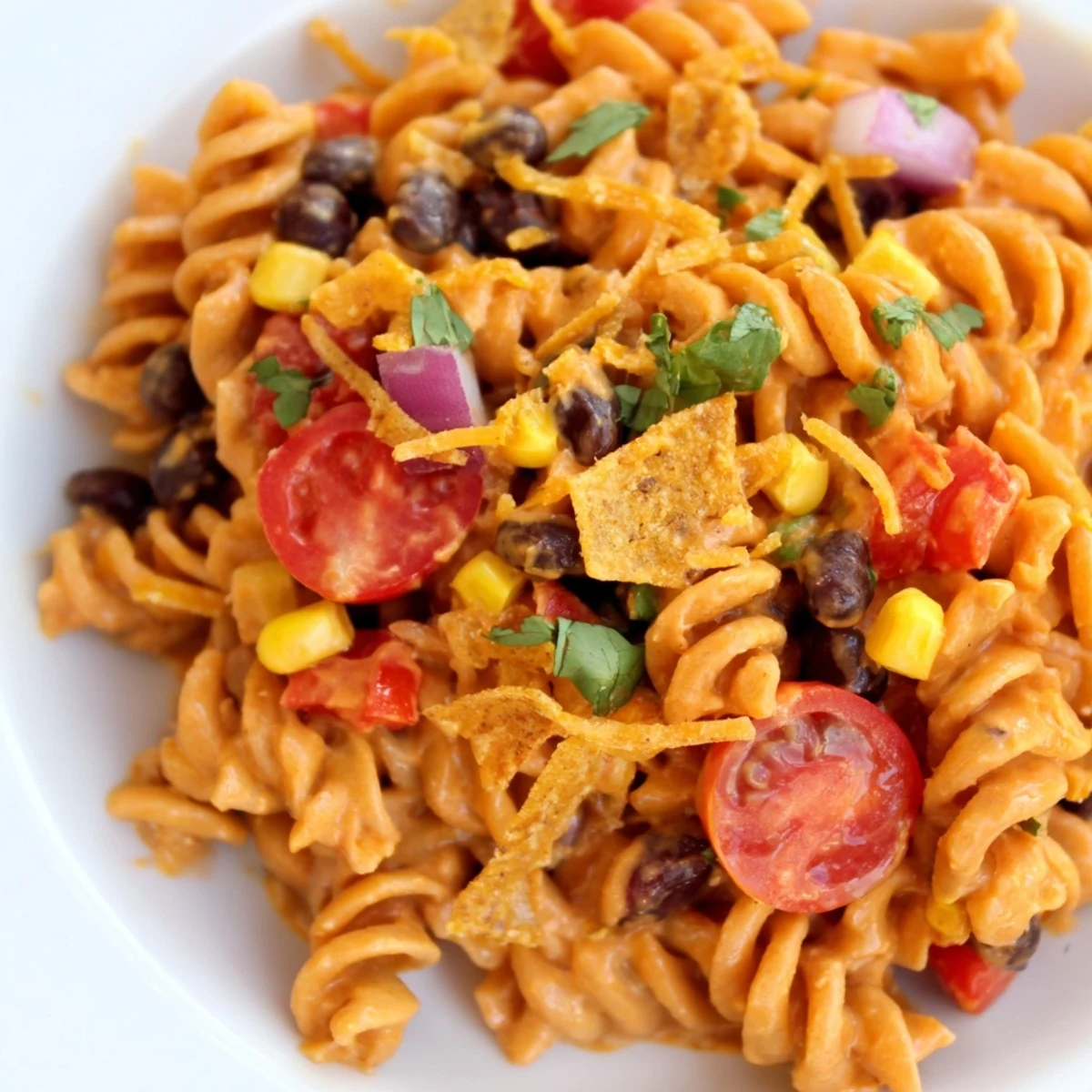 Creamy taco pasta salad topped with crunchy tortilla strips and fresh cilantro garnish