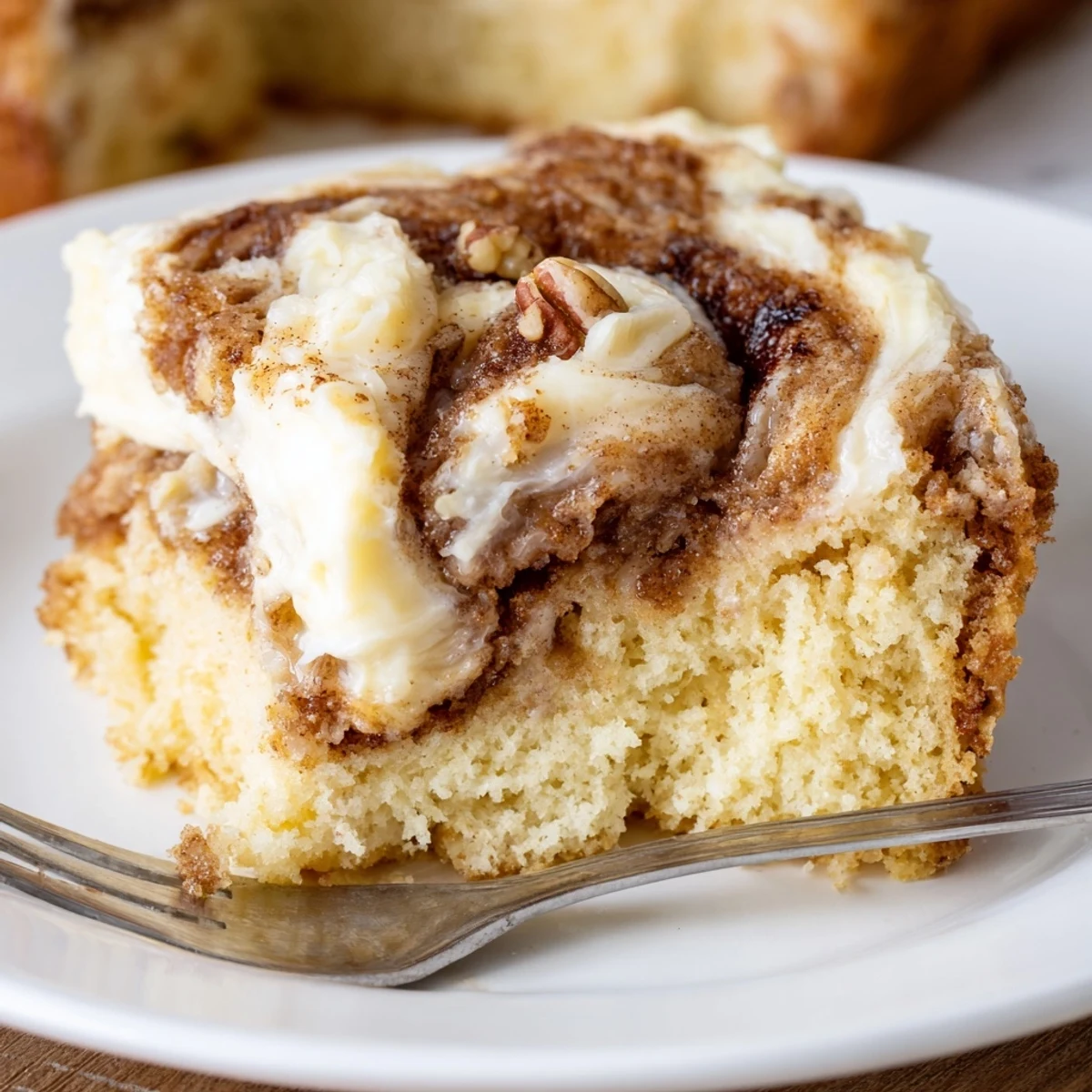 Cinnamon Roll Poke Cake with gooey cinnamon pockets and creamy frosting, sliced  