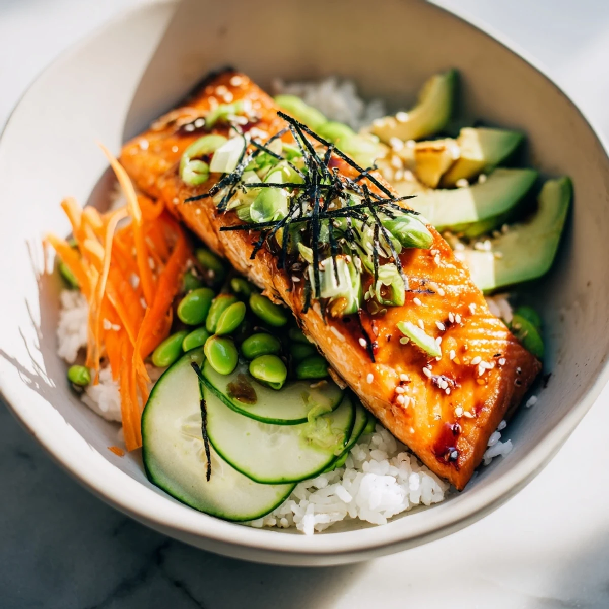Vibrant crispy salmon and rice bowl topped with avocado, cucumber, and savory soy ginger sauce drizzle