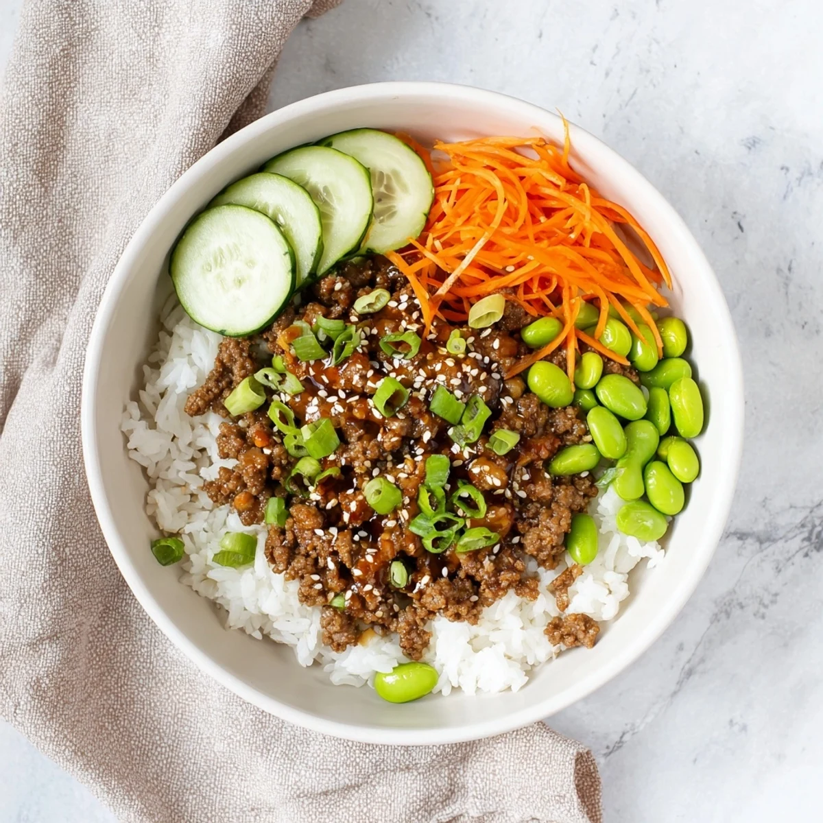Savory ground beef bowl featuring hot honey glaze, sesame seeds, and vibrant vegetable toppings over rice