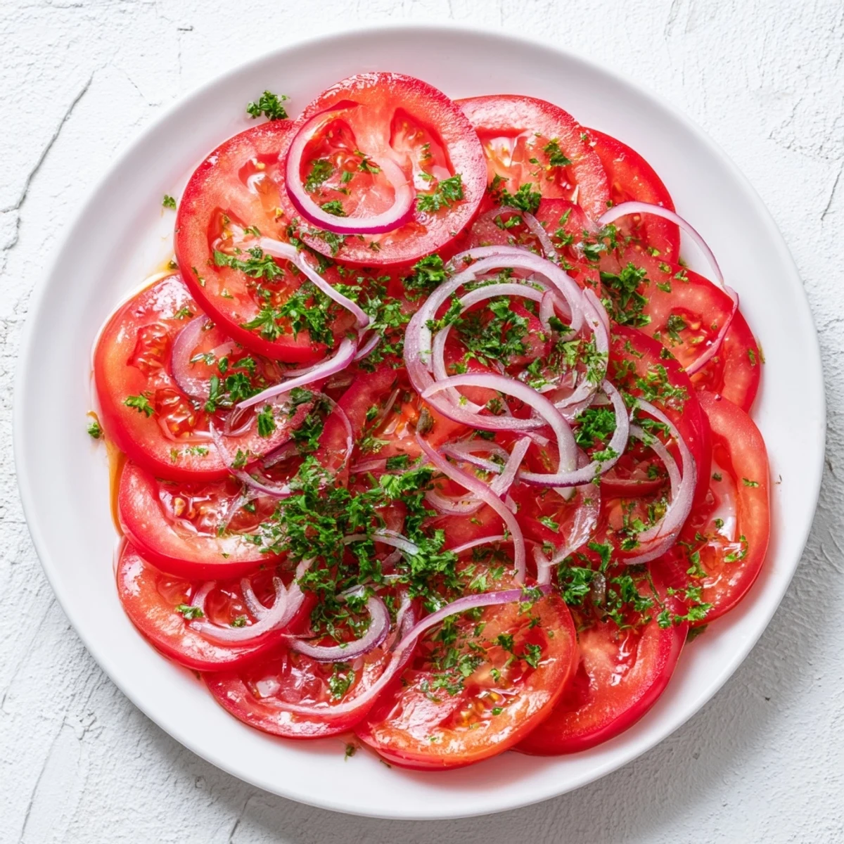 Crisp tomato and onion salad arranged on a white serving plate with light dressing