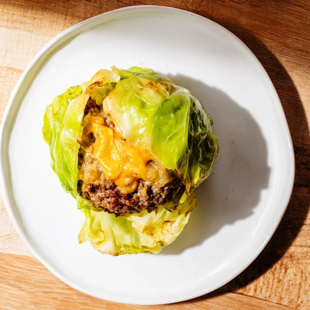 Juicy oven baked cabbage burger stuffed with seasoned ground beef and melted cheddar cheese, freshly baked