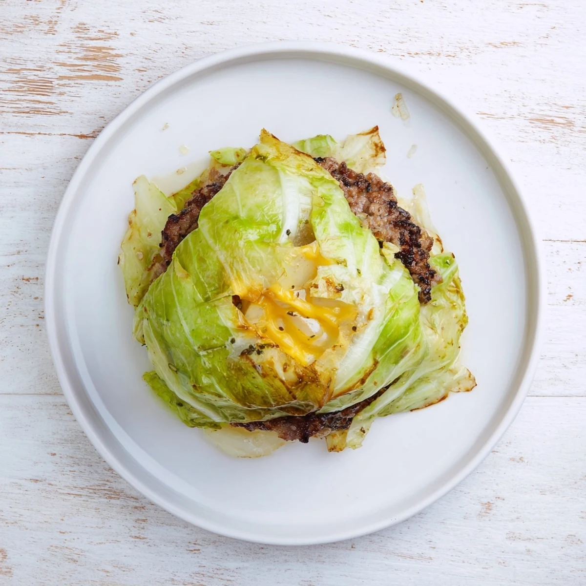 Low carb oven baked cabbage burger parcels garnished with fresh parsley on a wooden cutting board