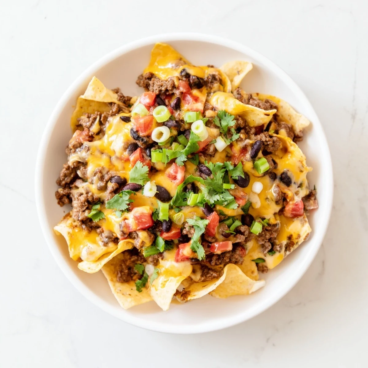 Creamy Super Nachos Dip with melted cheddar and Monterey Jack over seasoned ground beef, black beans, and jalapeños