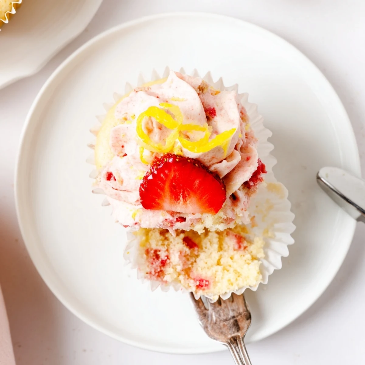 Plate of Strawberry Lemonade Cupcakes topped with diced strawberries and lemon zest