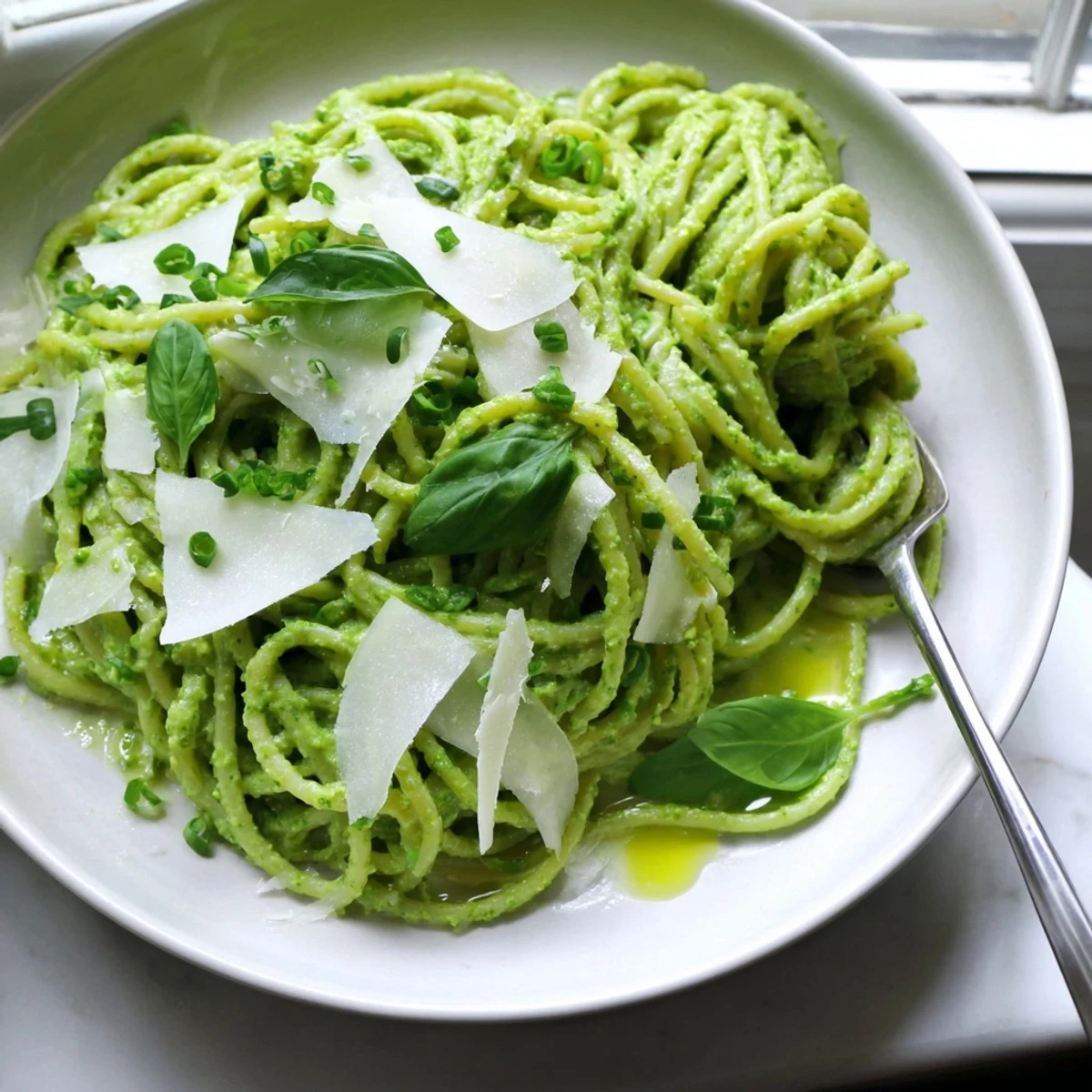 Creamy green goddess pasta sauce clings to twirled spaghetti in a rustic bowl