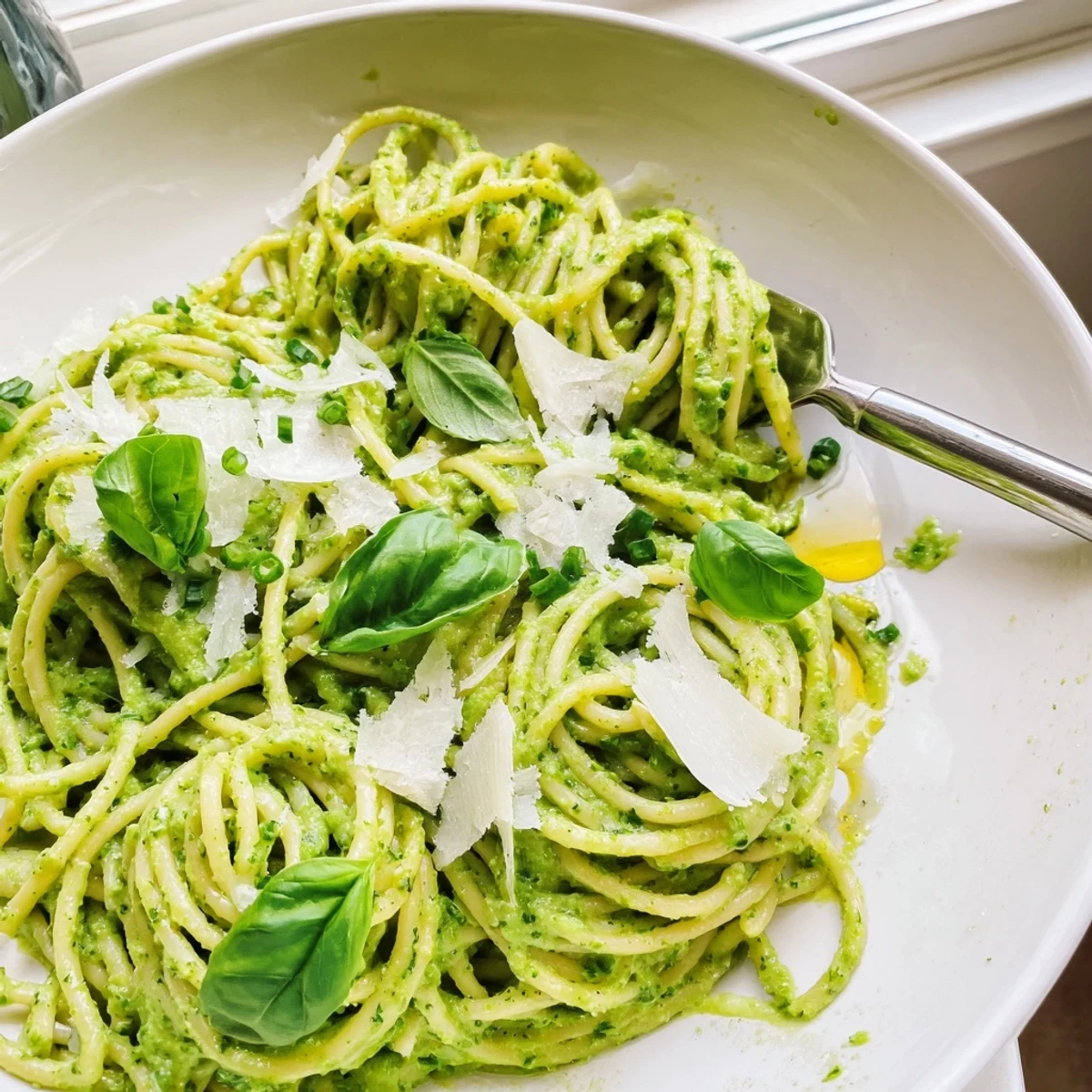 Bright herby green goddess pasta sauce topped with fresh basil and parmesan