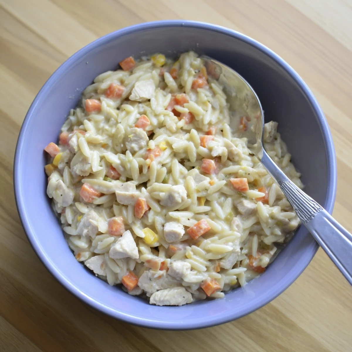 Creamy chicken pot pie orzo with tender chicken, vegetables, and melted cheese in a bowl.