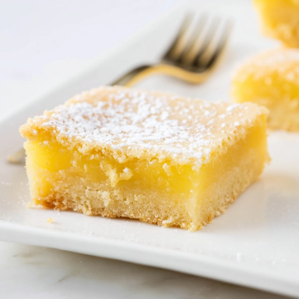 Golden simple lemon bars dusted with powdered sugar and resting on a wire rack