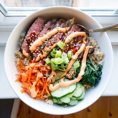 Savory sliced beef over fluffy rice with crisp veggies and kimchi