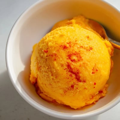 Velvety Creamy Chili Lime Mango Sorbet garnished with fresh lime zest and tropical fruit