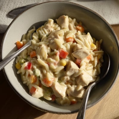 Steaming bowl of chicken pot pie orzo with peas, carrots, and creamy sauce.